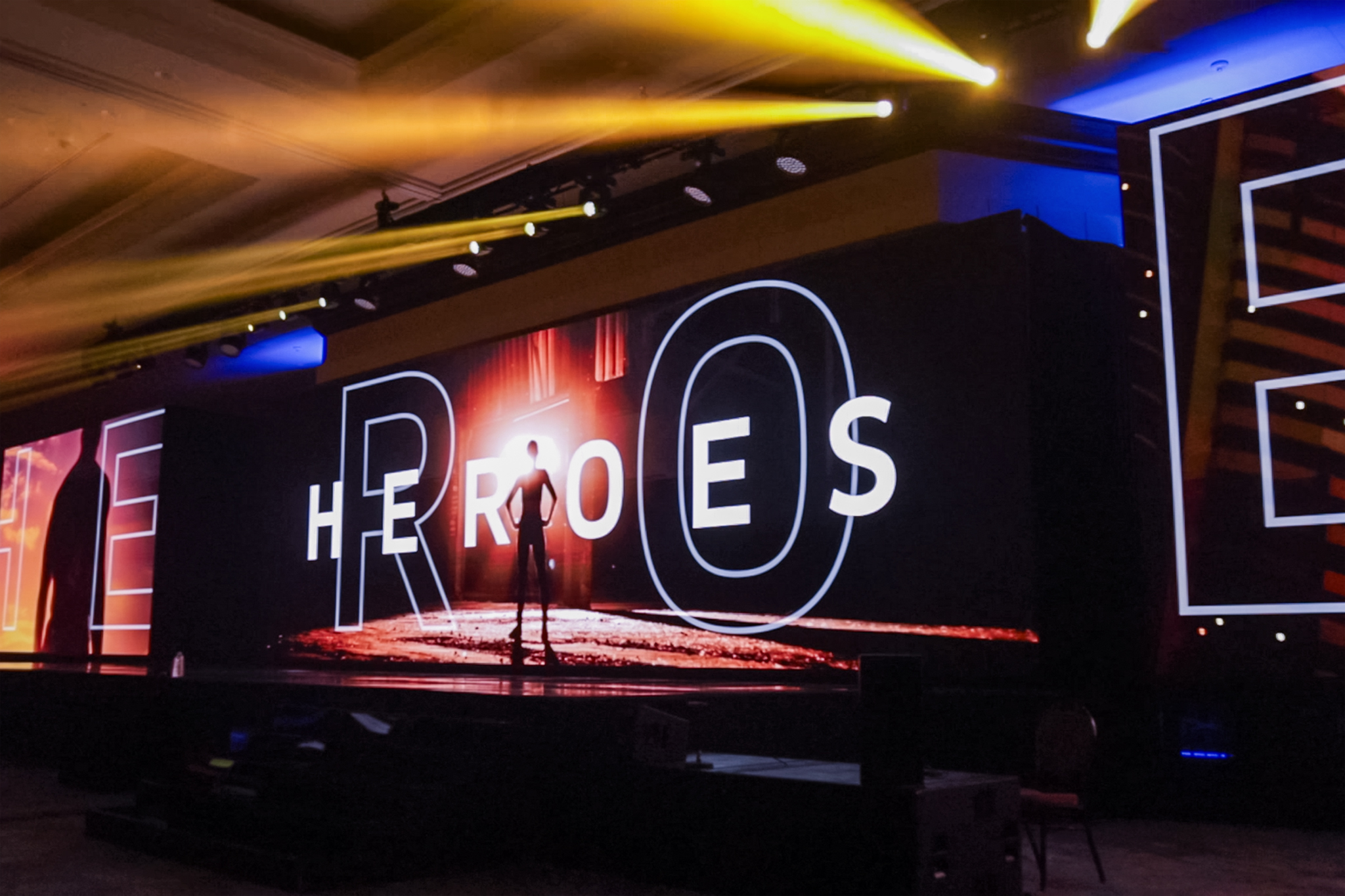A black step-front stage setup with LED walls and BIM lighting, customized to match the event’s brand colors